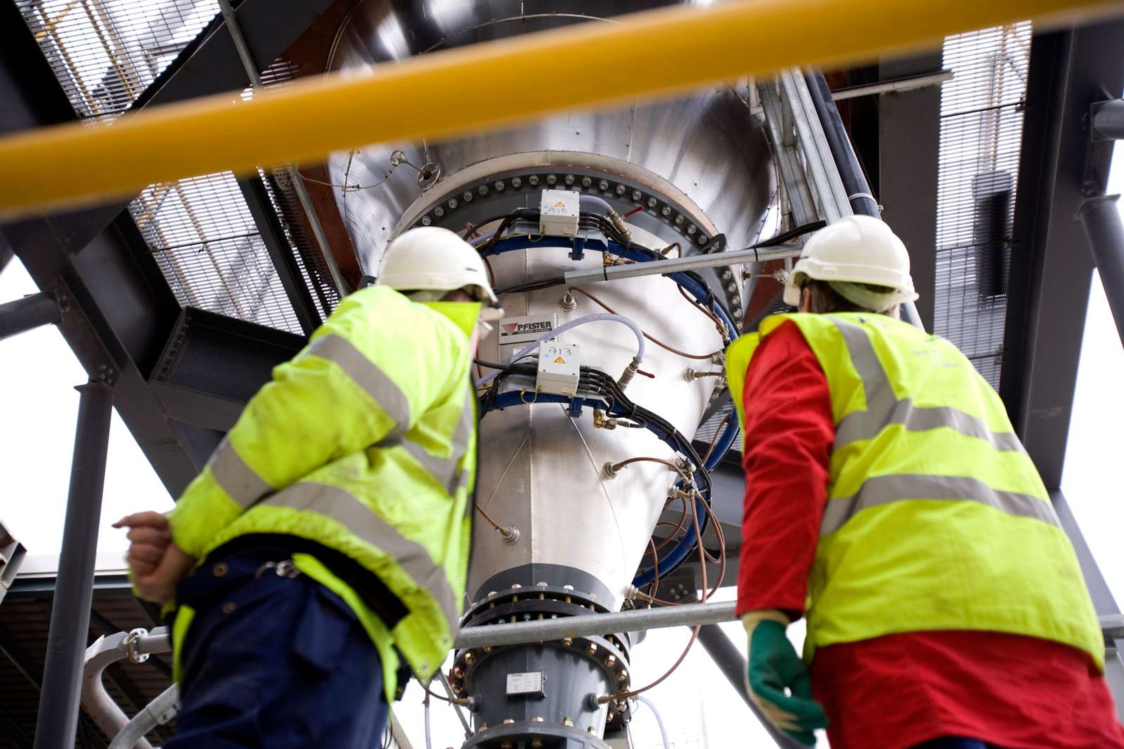 Engineers examining high-precision Pfister feeder system for consistent fuel dosing in cement production