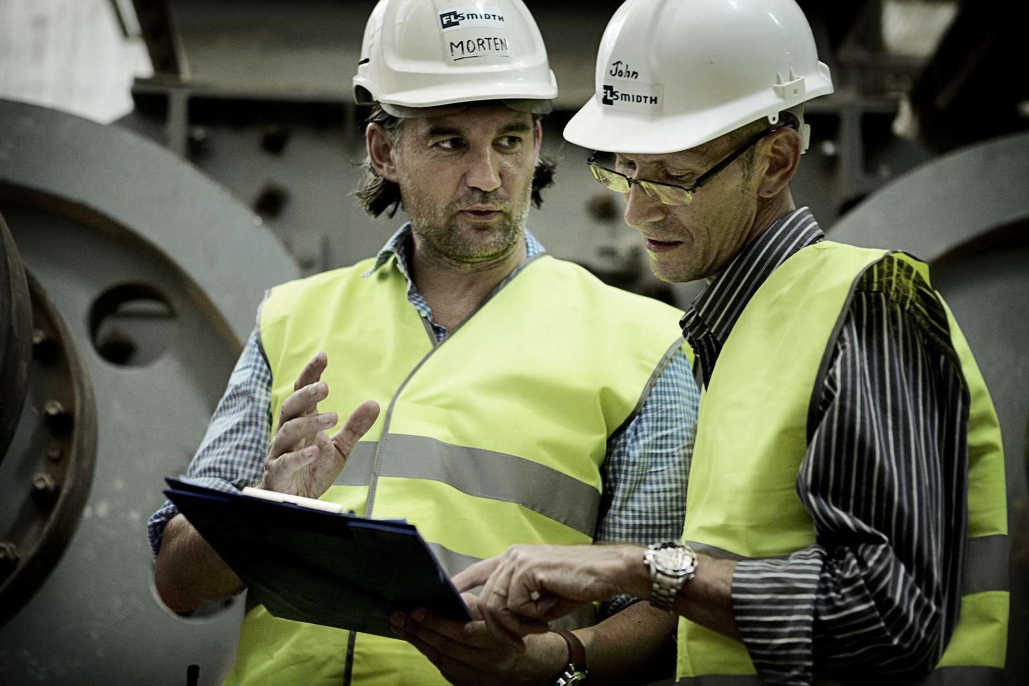 Fuller specialists discussing plant inspection report on-site in cement production environment